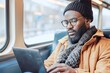 African men working with laptop remotely while traveling by train, blur train