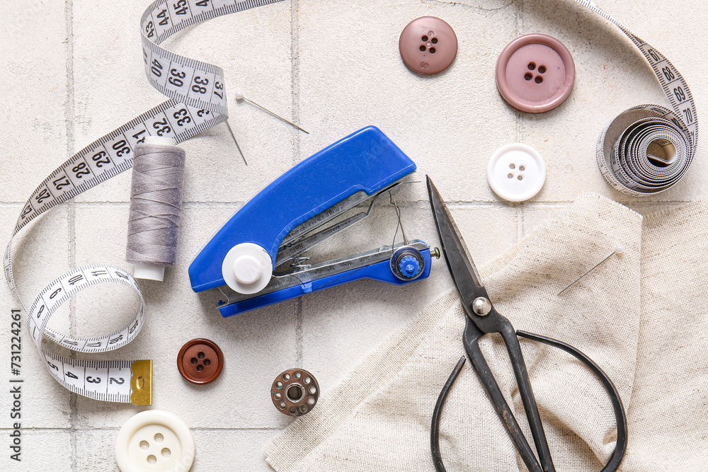 Manual sewing machine with different supplies on white tile background