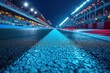 Asphalt racing track finish line and illuminated race sport stadium at night.
