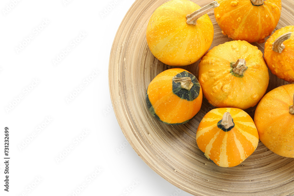 Plate with fresh pumpkins on white background