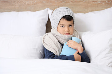 Poster - Ill little Asian boy with hot water bottle lying in bedroom