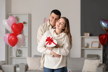 Sticker - Beautiful young couple with heart-shaped balloons hugging and celebrating Valentine's Day at home