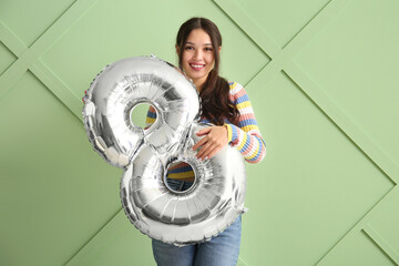 Sticker - Beautiful young Asian woman with silver air balloon in shape of figure 8 on green background. International Women's Day