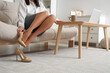© Pixel-Shot - Businesswoman taking off high heels on sofa at home