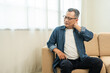 © Chanakon - Old man senior has problem with structural posture He had neck and shoulder pain. Mature Massaged his neck and shoulders for relief. reduce muscle tension. Sitting on sofa couch in living room