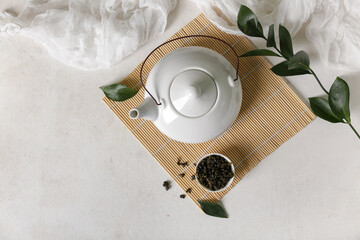 Wall Mural - Bamboo mat with teapot and bowl of dry tea on light background