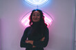 © BullRun - Smiling woman standing against glowing neon sign