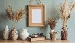 empty wooden picture frame mockup hanging on pastel wall boho shaped vases with dried flowers and house plants on table working space home office modern interior technology
