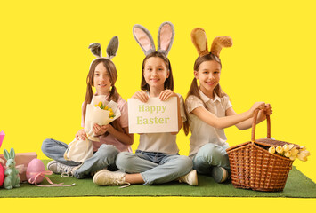 Wall Mural - Cute little girls celebrating Easter on yellow background