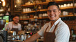 © MP Studio - two smiling men in a cafe, one in the foreground wearing a white shirt and leather apron
