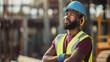 © Studio Nova - A construction worker with a blue safety helmet and reflective vest stands with crossed arms, looking intently at a construction site.