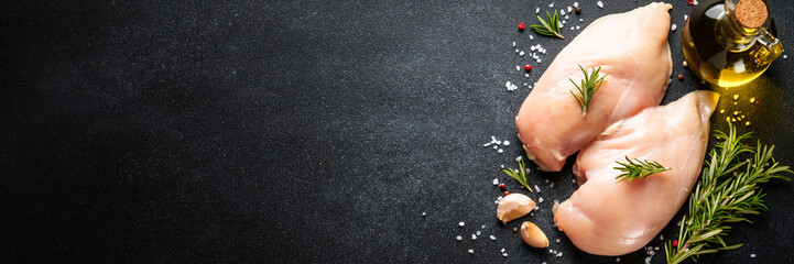 Sticker - Uncooked chicken breast with spices at black table. Long banner format.