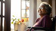 happy senior retired african american woman sitting in a wheel chair looking outside of the window