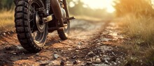 A Rugged Motorcycle Kicks Up A Cloud Of Dust As It Tears Through The Grassy Field, Its Tire Treads Gripping The Soil With Determination On The Rough Dirt Road