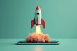 © Kaleb - Rocket taking off from cell phone screen on green background, startup concept