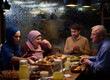 © .shock - A modern and traditional European Islamic family comes together for iftar in a contemporary restaurant during the Ramadan fasting period, embodying cultural harmony and familial unity amidst a