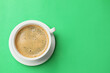 canvas print picture - Aromatic coffee in cup on green background, top view. Space for text