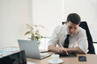 © Parichat - Young business man working in office with laptop and papers on desk, Businessman working on a laptop computer in the office, Businessman working in a new office