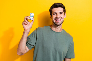 Sticker - Portrait of cheerful smart guy with stubble wear stylish t-shirt hold mondey get passive income isolated on yellow color background