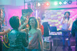 © DC Studio - Girlfriends talking while relaxing on dancefloor at nightclub discotheque. Smiling women dancing together while partying and attending live electronic music concert in club