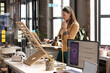 © Wavebreak Media - Young Caucasian woman works at a standing desk in a casual business office