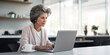 © ImageFlow - Senior businesswoman focused on laptop in a bright contemporary office. Productivity concept Generative AI