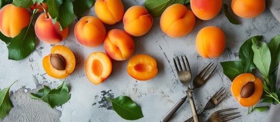 Wall Mural - Organic apricots, both whole and halved, displayed on a light gray backdrop with utensils.