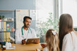 © dsheremeta - A young male pediatrician with a tablet in his hands consults a mother with her little daughter. The concept of a children's doctor appointment.