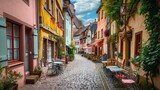 Fototapeta Na drzwi - Quaint European street with colorful facades and cobblestones. A picturesque cobblestone street lined with colorful buildings and outdoor cafes in a quaint European town. Resplendent.