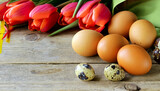 Fototapeta Tulipany - Easter composition with eggs and flowers on a wooden background