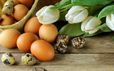 Fototapeta Tulipany - Easter composition with eggs and flowers on a wooden background