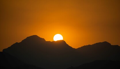 Wall Mural - Beautiful orange and pink sunset sky in the backdrop of a majestic mountain range