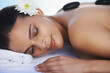 Sleeping, hot stone or woman with flower in spa for wellness, treatment or hospitality. Relax, resort or salon with female person, client or masseuse in hotel on holiday vacation for beauty therapy