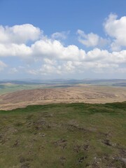 Wall Mural - the grassy hills and plains of a valley under a blue sky with white clouds