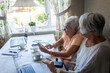 © Johnér - Elderly woman using smart phone sitting by female friend at home