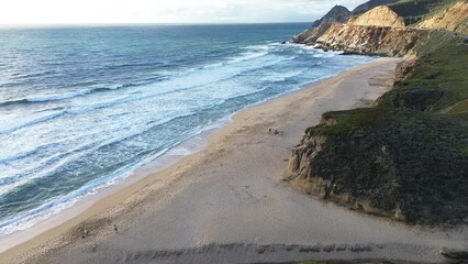 Sticker - Aerial of the foamy waves of the sea hitting the sandy beach on a sunny day