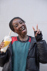 Portrait of cheerful young woman giving peace sign