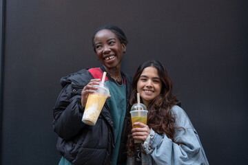 Wall Mural - Portrait of two cheerful women drinking bubble tea 