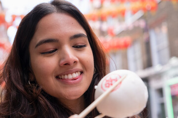 Wall Mural - Young woman eating steamed bun in Chinatown