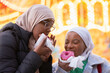 Young female tourists in hijabs eating donuts