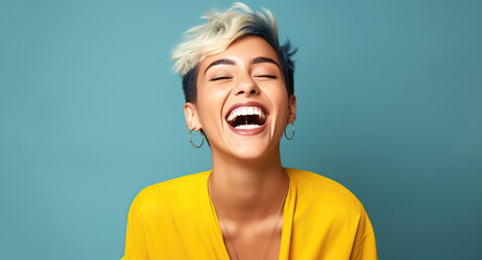 Wall Mural - Portrait of a young laughing woman with blond short hairstyle. Isolated over blue background.