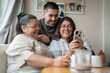 © Cultura Creative - Three-generation family taking selfie at home