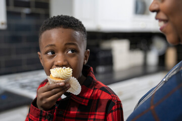 Boy with grandmother tasting fresh baked cupcakes