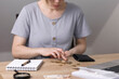 The woman at the table counts the money poured out of her purse. On the table is a notebook with a pen for writing, a magnifying glass and euro money. copy space. High quality photo