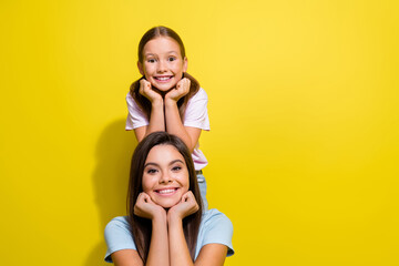 Poster - Photo of dreamy adorable small siblings dressed t-shirts arms cheeks smiling empty space isolated yellow color background