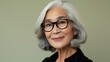 © iuricazac - A smiling elderly woman with white hair and black glasses wearing a black top against a neutral background.