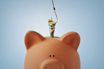 Piggy bank with money and fishing hook - Concept of phishing and stealing money