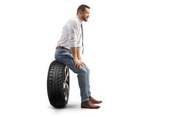 Wall Mural - Profile shot of a man sitting on a car tire and thinking