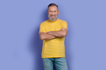 Wall Mural - Photo of cool handsome retired man with gray white beard dressed striped t-shirt standing arms crossed isolated on purple color background