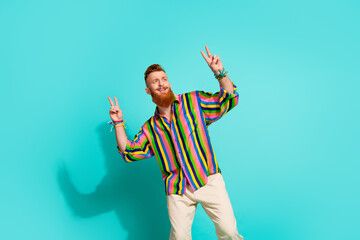 Photo of cheerful red hair beard male model hipster showing double v sign looking empty space isolated on aquamarine color background